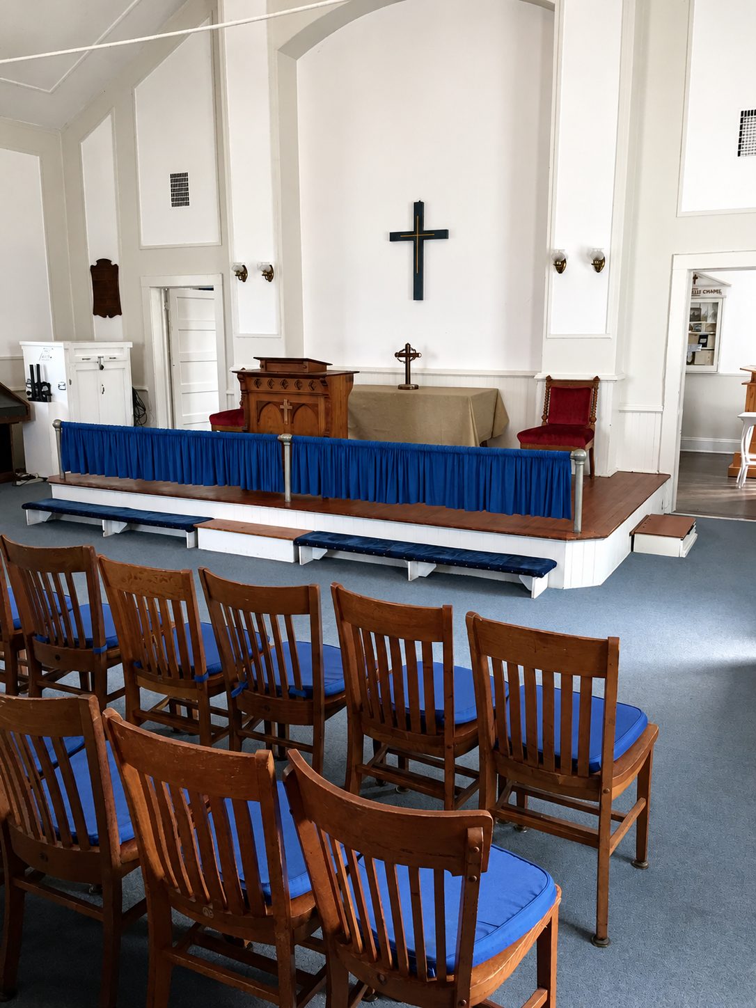 Chapel interior with wooden chairs, raised platform, and cross