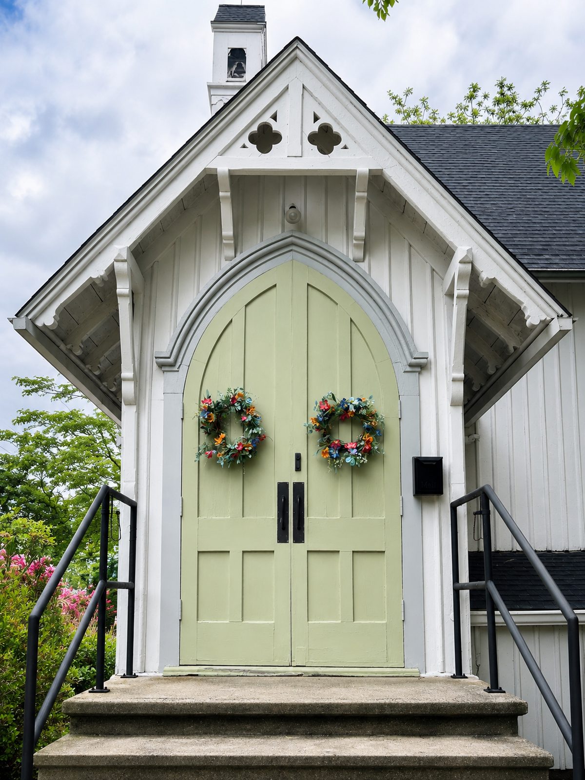 The arched entrance of Griswoldville Chapel, sage green doors with flower wreaths.