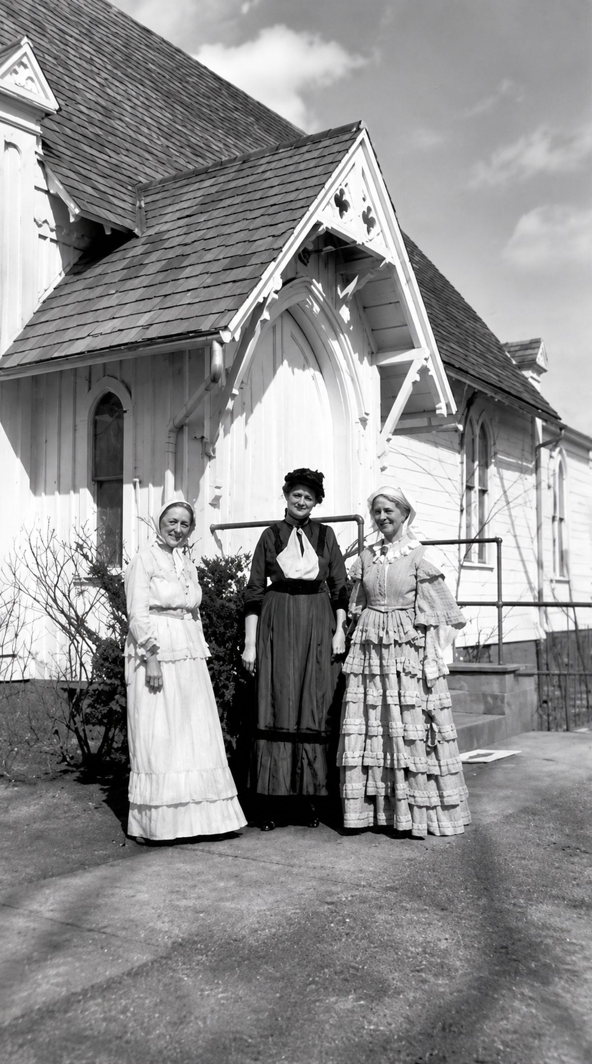 Three women in period dress outside the chapel entrance